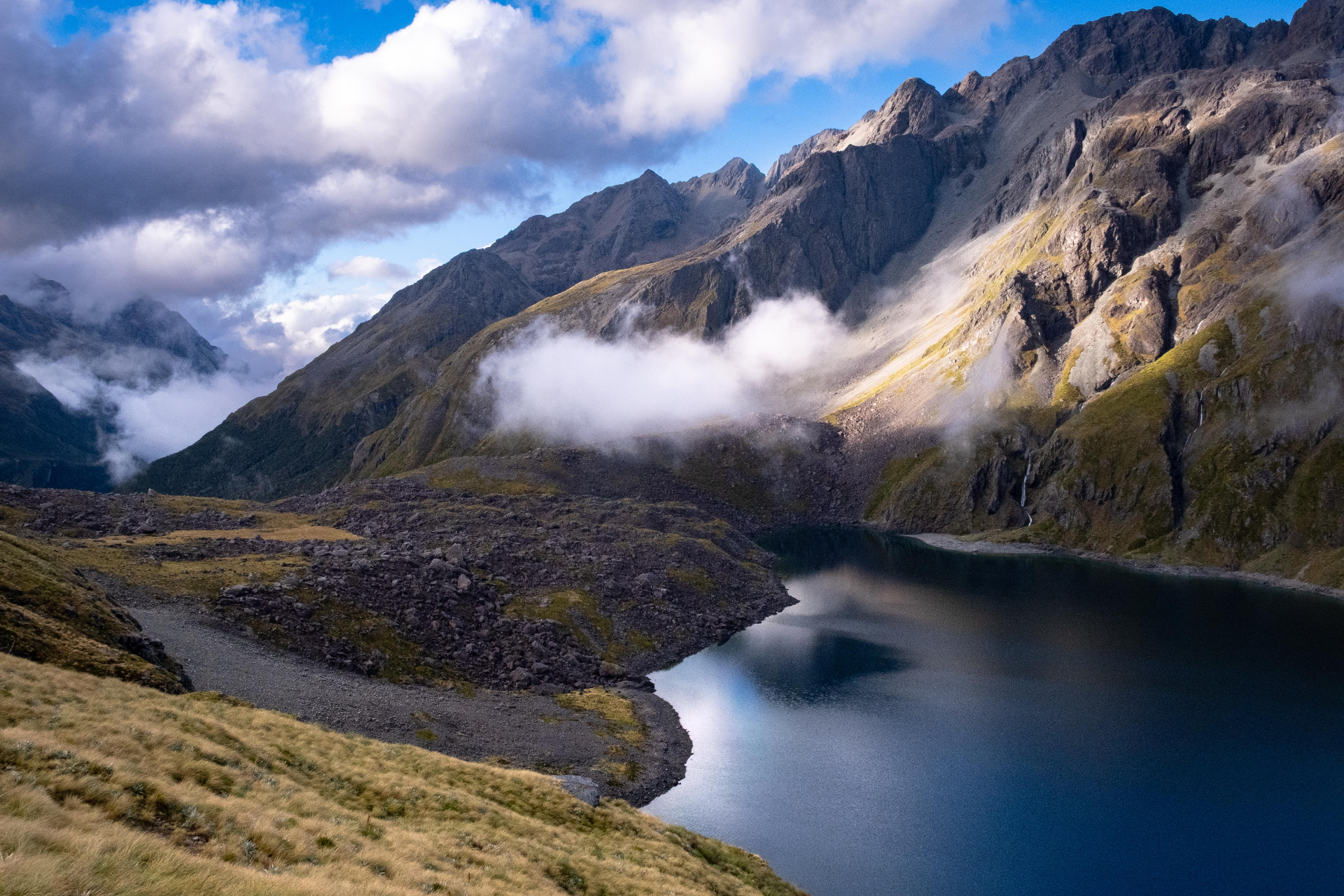 Alpine lake below cloud-wreathed peaks